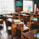 An empty vintage classroom with wooden desks and books on each desk, reflecting a classic educational setup.
