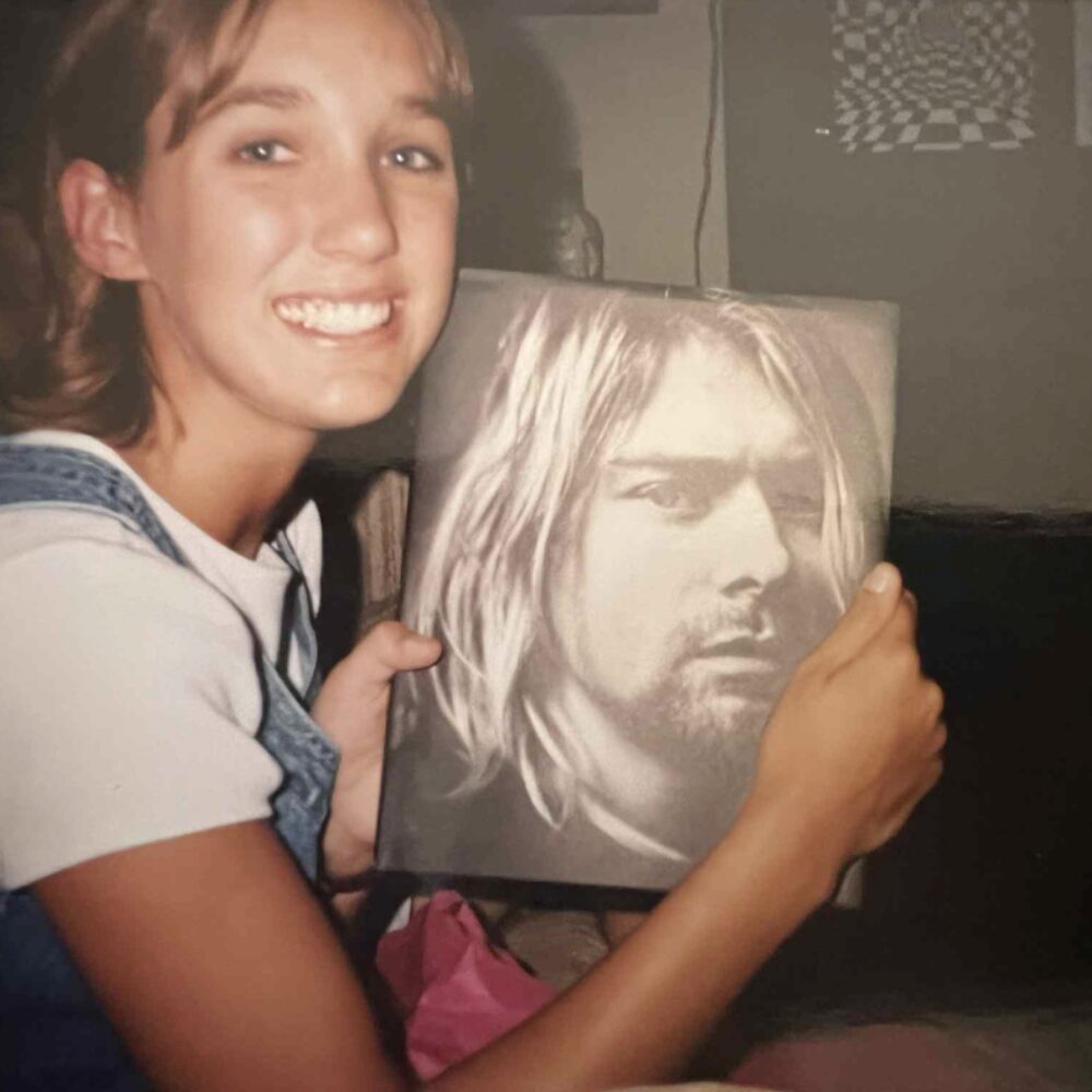 Teen holding a Nirvana book in the 1990s, representing physical media ownership before streaming.