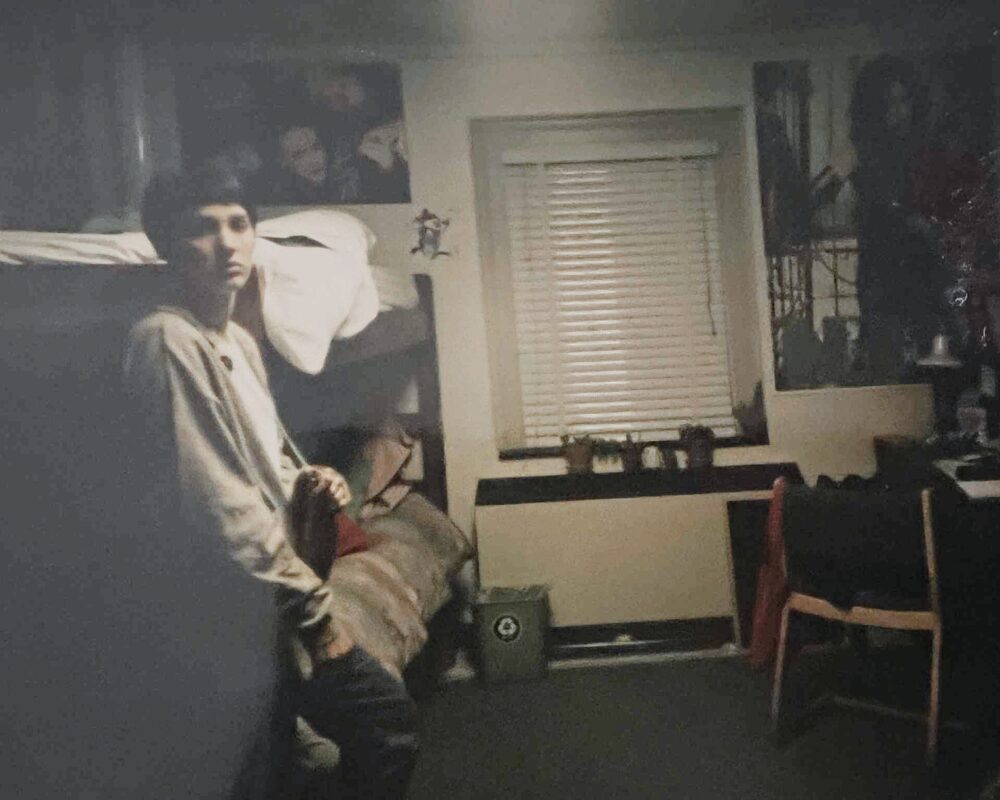 Dimly lit 1990s dorm room with band posters on the wall, reflecting pre-streaming music culture.