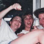 Four friends laughing together on a couch in the 1990s, captured on film before the era of social media documentation.