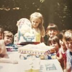 Girl opening a Birthday Bear Care Bear at a 1984 birthday party surrounded by friends