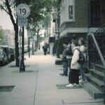 Teenagers standing on a city sidewalk in a moody, 1990s-inspired urban setting
