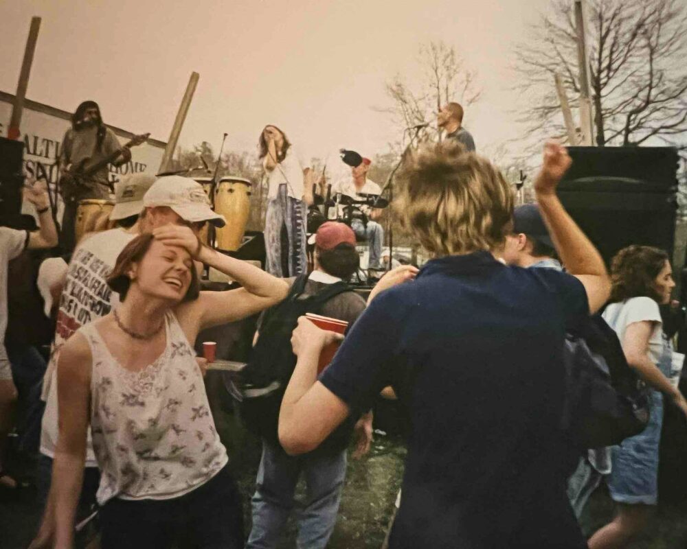 Young people dancing at an outdoor music festival wearing 1990s thrift-store and grunge-inspired clothing