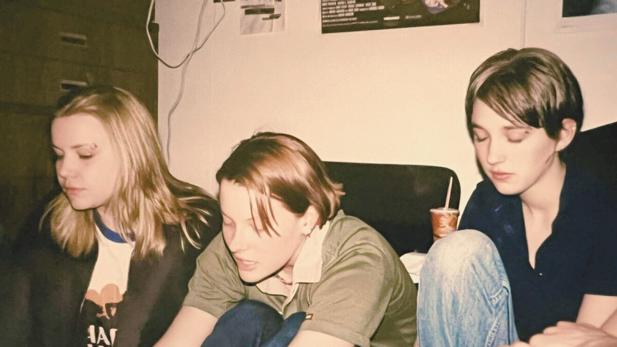 Group of teenage friends hanging out together in the 1990s, music playing in the background