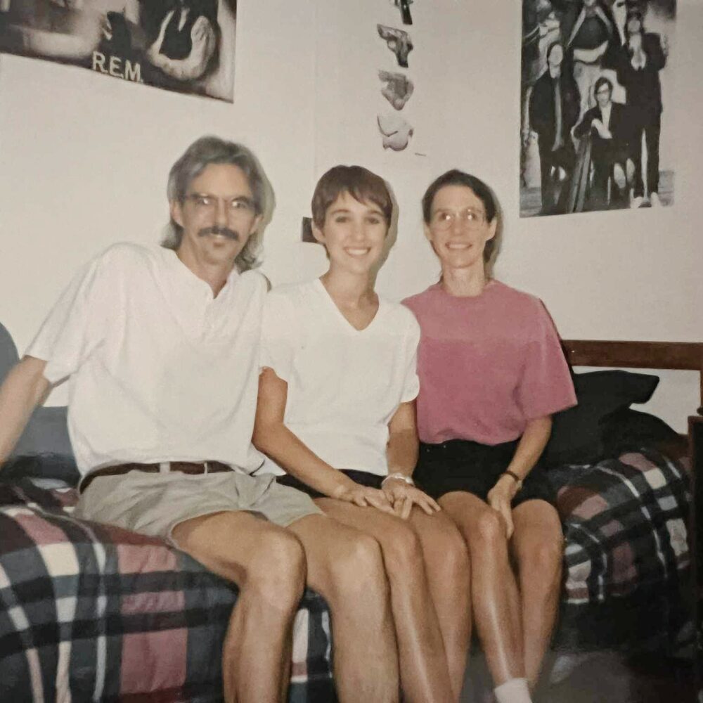 Family photo in a 1990s dorm room with music posters on the wall